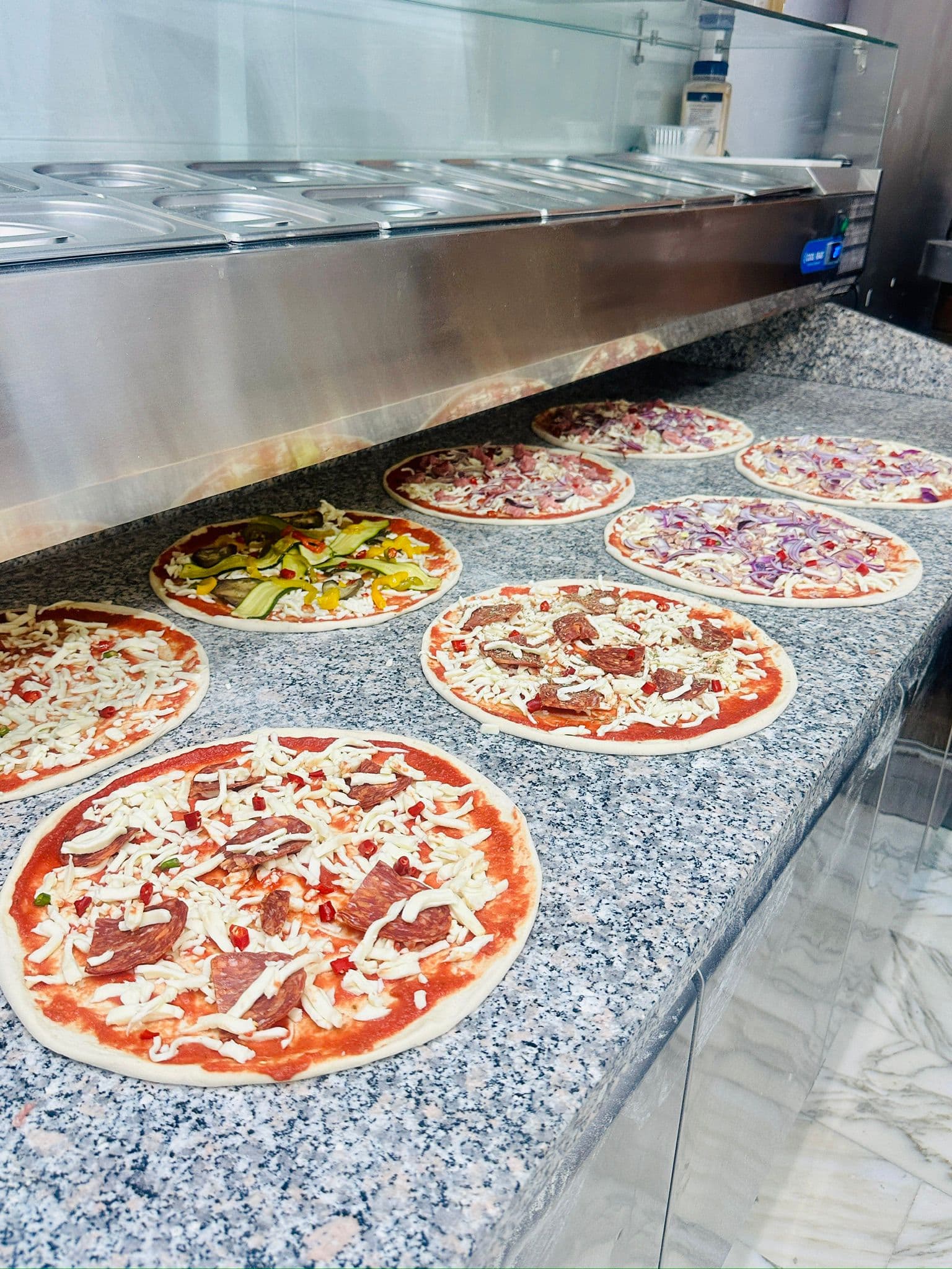 Pizze in preparazione sul bancone del laboratorio